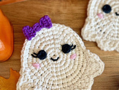 A Crochet Ghost Coaster called the Ghoster. White Halloween coaster laying on a wood table.