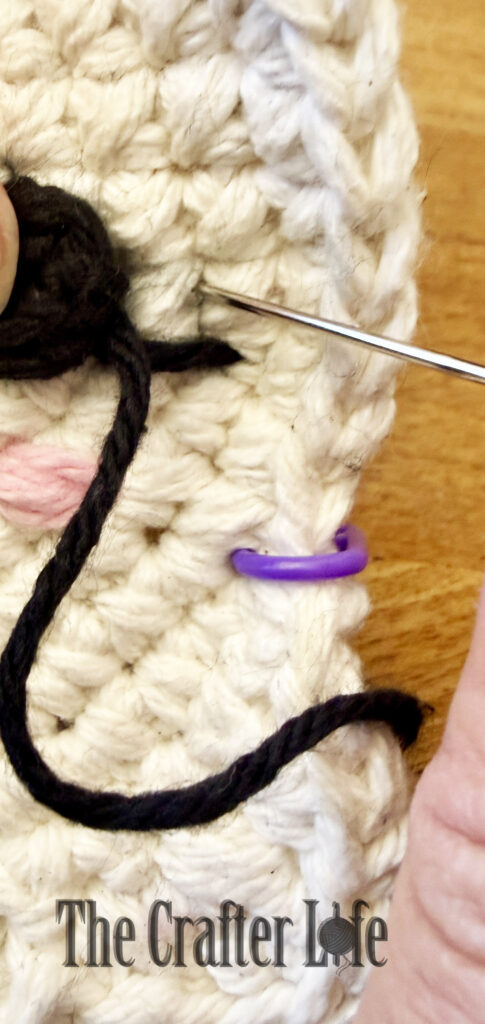 white crochet ghost coaster on a wooden table.